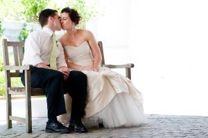 a bride and groom sitting on a bench kissing at Evertsdal Guesthouse in Durbanville +79 photos