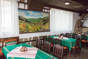 a restaurant with tables and chairs with a painting on the wall at Hotel Uzunski in Smolyan