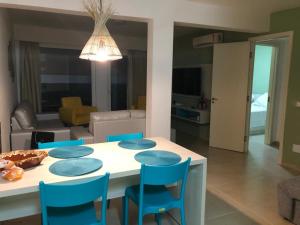 a living room with a table and blue chairs at Apart Hotel Praia dos Carneiros Apto 101 in Praia dos Carneiros