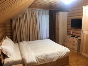 a bedroom with a white bed and a television at Коттедж Luky in Migovo