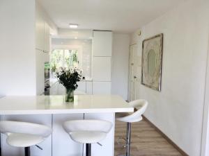 una cocina con encimeras blancas y taburetes blancos en Panoramic Apartments Sitges, en Sitges