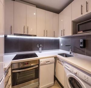 a kitchen with white cabinets and a washer and sink at Mon Suites Catedral in Valencia