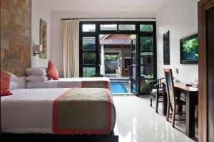 a hotel room with two beds and a dining table at Villa Teman in Lovina