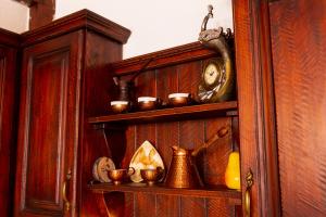 a wooden shelf with cups and a clock on it at Grancharova Guest House in Bansko