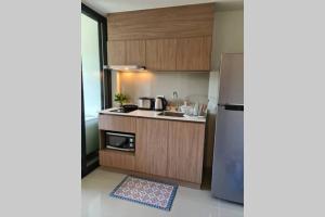 a kitchen with wooden cabinets and a stainless steel refrigerator at Hua Hin La Casita modern room in city centre in Hua Hin