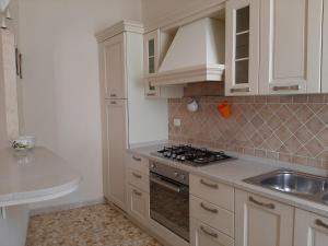 a kitchen with white cabinets and a sink and a stove at APPARTAMENTO CASA MARCO in Capoliveri