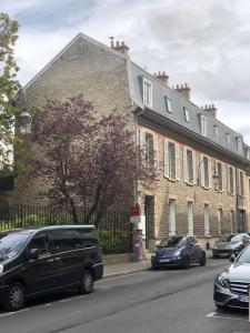 un gran edificio de ladrillo con coches estacionados frente a él en Centre ville - Appartement 3 chambres & Terrasse - La Clé des Sacres en Reims