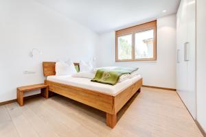 a bedroom with a bed with white walls and a window at Appartement Valbona Blick by A-Appartments in Bürserberg