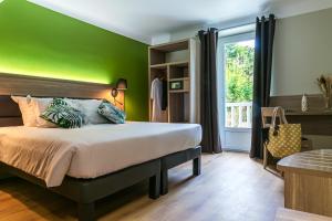 een slaapkamer met een bed met een groene muur bij Hôtel du Pont in Ascain