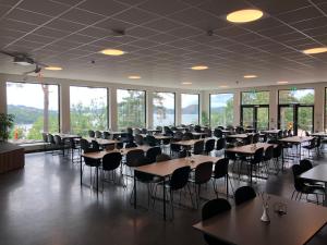 a large room with tables and chairs and windows at Ansgar Summerhotel in Kristiansand