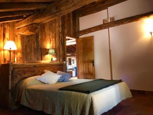sypialnia z łóżkiem w pokoju z drewnianymi ścianami w obiekcie Casona de Saltus, espectacular casona en Sotosalbos,10min de Segovia w mieście Sotosalbos