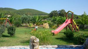 um parque infantil com um escorrega cor-de-rosa num quintal em Agriturismo Isidoro em Fertilia