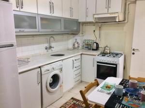 a kitchen with a washer and a stove and a table at Comfy Flat 2 No Air Condition but has ceiling fans and central Heating in Denizli