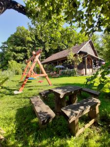 a picnic table and two benches in a park at Kuća Viola, traditional wooden house in Tuhelj in Tuhelj