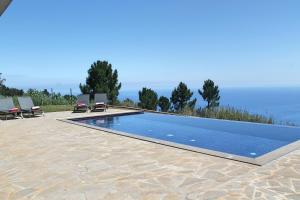 une piscine avec deux chaises longues à côté dans l'établissement OurMadeira - Quinta Inácia, countryside escape, à Calheta