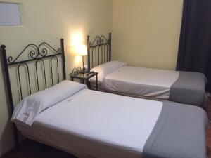 two beds in a room with white sheets at Hospedería Luis de Góngora in Córdoba