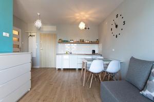 a kitchen and living room with a table and chairs at Apartament SUNtorini in Kołobrzeg