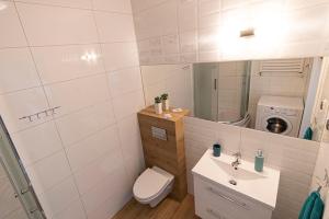 a bathroom with a sink and a toilet and a mirror at Apartament SUNtorini in Kołobrzeg