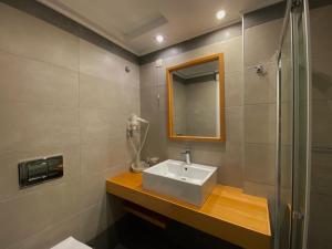 a bathroom with a sink, mirror, and bathtub at Mirini Hotel in Samos