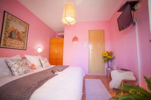 a bedroom with a large bed with pink walls at Roso in Gradac