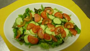 a salad with tomatoes and lettuce on a white plate at Agriturismo Isidoro in Fertilia