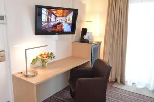 une chambre d'hôtel avec une télévision et une chaise dans l'établissement Hotel Krone, à Pforzheim