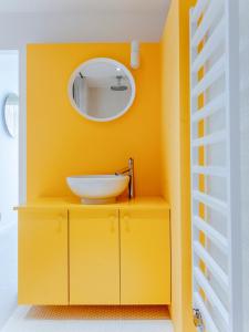 a yellow bathroom with a sink and a mirror at Jupiter Silesian Place Apartments in Katowice