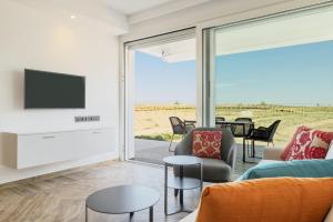 a living room with a tv and a couch and chairs at Hapimag Apartments Cavallino in Cavallino-Treporti