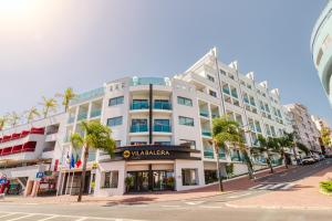 a large white building on a street with palm trees at Vila Baleira Funchal in Funchal