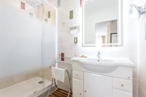 uma casa de banho branca com um lavatório e um chuveiro em Hotel Le Centre em Gramat