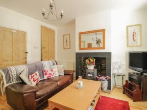 a living room with a leather couch and a fireplace at All Saints View in Cockermouth