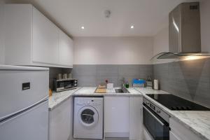 a kitchen with a washer and dryer in it at Collingham Serviced Apartments in London