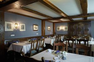 une salle à manger avec des tables, des chaises et un tissu de table blanc dans l'établissement Landhotel & Gasthof Cramer, à Warstein