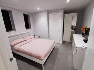 a white bedroom with a bed with pink pillows at 4 sleeps and travel cot- close to beach and restaurants in Bournemouth