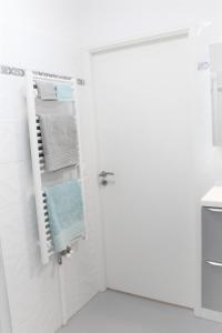 Baño blanco con puerta y toallas en Appartement tout équipé, cosy (1 station de Paris) en Saint-Denis