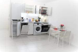 cocina blanca con lavadora y mesa en Appartement tout équipé, cosy (1 station de Paris) en Saint-Denis