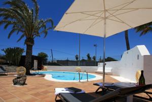 a pool with an umbrella and two chairs and a table with an umbrella at Hotel Rural Finca de La Florida in San Bartolomé