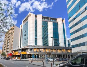 un grand bâtiment dans une rue de la ville avec des voitures garées devant dans l'établissement Hotel Ismira, à Izmir