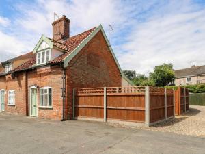 a red brick house with a wooden fence at Bridge End Cottage in Norwich