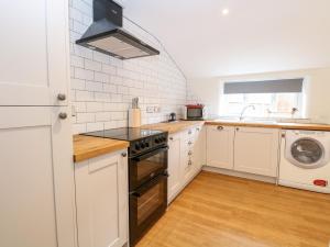 a kitchen with white cabinets and a stove top oven at Bridge End Cottage in Norwich