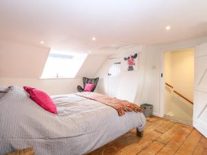 Bridge End Cottage في نورويتش: غرفة نوم مع سرير مع وسائد وردية عليه