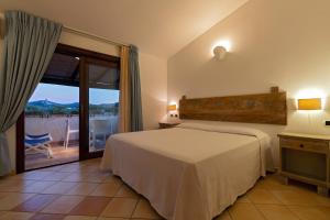 a bedroom with a bed and a balcony with a view at Porto Giunco Residence in Villasimius