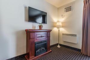 a room with a fireplace and a flat screen tv at Hôtel Le Principal in Granby