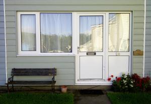 a house with two doors and a bench in front at Freshwater Bay Holiday Cottages in Pembroke