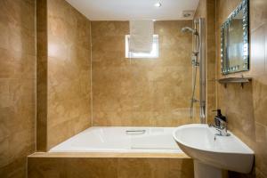 a bathroom with a tub and a sink at The Stamford in Southport