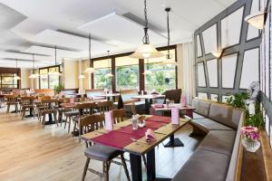 Un restaurante con mesas, sillas y ventanas. en Landhotel Kuralpe Kreuzhof, en Lautertal
