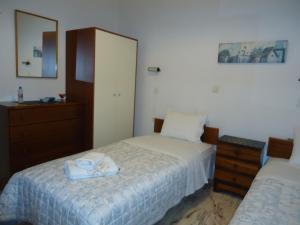 una camera con due letti, un comò e uno specchio di Ενοικιαζόμενα δωμάτια "ΟΛΓΑ" a Loutra Ipatis
