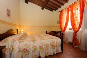 una camera da letto con un letto e due finestre con tende di Country House Il Piancardato a Collazzone Altre 54 foto