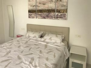 1 cama en un dormitorio con 2 pinturas en la pared en Entremares en Lo Pagán