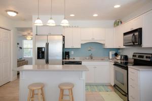 a kitchen with white cabinets and a kitchen island with stools at Charming Beachside Home by Ocean Properties in New Smyrna Beach